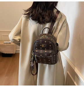 Close-up of a dark brown mini backpack with bear monogram and gold hardware accents