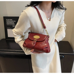 Macro shot of retro dark red leather shoulder bag featuring gold buckle and textured finish