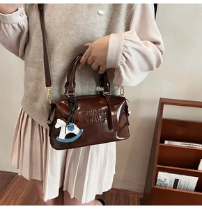 Detail of glossy brown leather Boston bag with embossed logo and horse charm