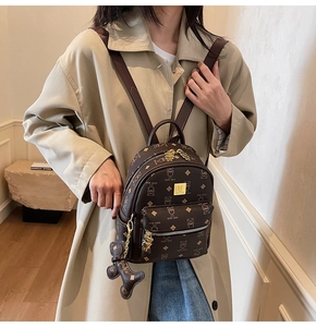 Detail view of mini brown backpack with bear print and cute charm on beige trench coat