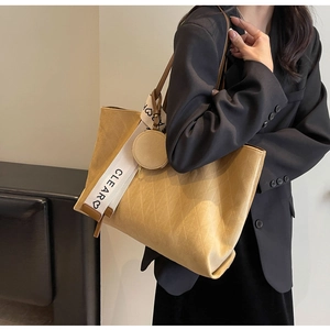 Detail of yellow quilted tote bag with wide strap and round coin purse accessory