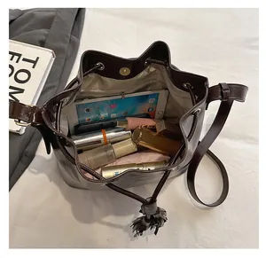 Sac seau marron foncé avec pompon montrant l'espace intérieur pour tablette et cosmétiques