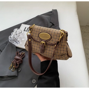Detail of vintage houndstooth handbag with dark brown leather trim and golden metal buckle
