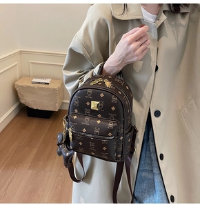 Close-up of brown bear pattern backpack with gold logo and matching teddy bear charm