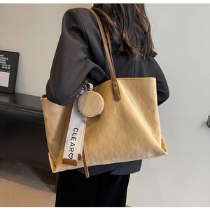 Detail of beige quilted tote bag with a small round pouch and a CLEAR letter strap
