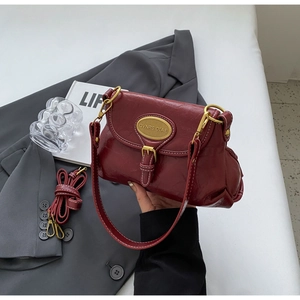 Detailed view of burgundy vintage handbag with glossy wrinkled leather and gold hardware