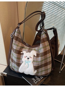 Plaid tote bag with plush dog embroidery and brown leather strap on mirror display