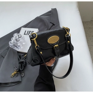Detail of vintage black crossbody bag with gold buckle and white contrast stitching