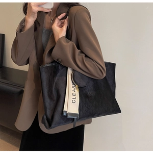 Detail of black suede tote bag with diamond stitching and CLEARC lettered strap