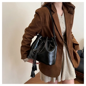 Détail d'un sac seau noir brillant à cordon avec d'élégants glands doubles sur la bandoulière