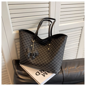 Detail of MK monogram tote bag with leather handles and animal charm accessory