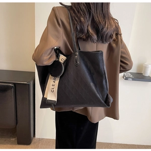 Detail view of large black suede tote bag with lettered strap and small coin purse accessory