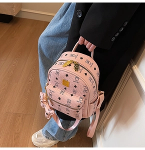 Detailed macro shot of pink faux leather backpack featuring teddy bear pattern and golden zipper