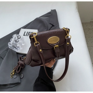 Detail of vintage dark brown crossbody bag with gold hardware and smooth leather texture