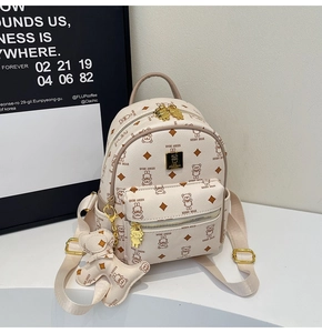 Detail of cream backpack featuring bear print pattern and a matching bear plush charm