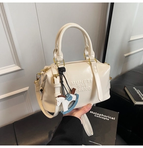 Close-up of cream Boston bag featuring letter embossing and a cute pony charm detail