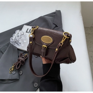 Detail of vintage brown leather shoulder bag with gold metal plaque and spare strap