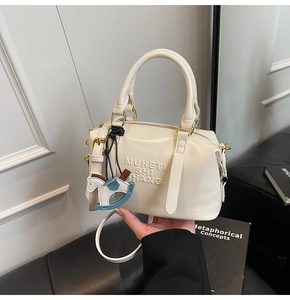 Detail of cream white Boston handbag with embossed letters and cute horse pendant