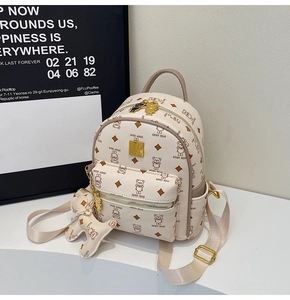 Detail view of cream leather mini backpack with bear patterns and gold metal zipper