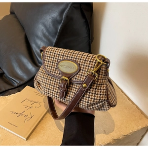 Close-up of vintage houndstooth crossbody bag with brown leather trim and gold hardware logo