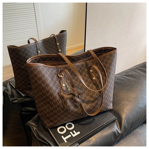 Detailed view of the dark brown monogram tote bag on a black leather sofa surface