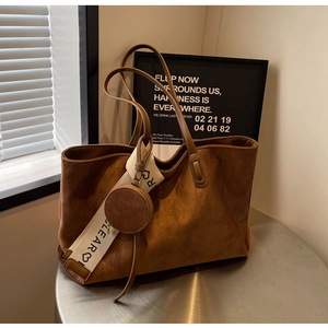 Detailed view of brown suede tote bag with woven CLEAR strap and small round coin purse