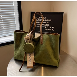 Detail of dark green suede tote bag with quilted diamond pattern and a small coin purse