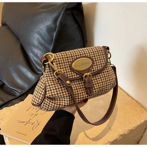 Detail of retro houndstooth pattern bag with premium brown leather trim and gold emblem