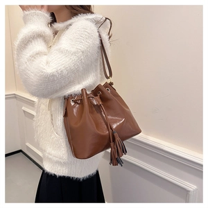 Sac seau marron brillant avec cordon de serrage et pompon porté en bandoulière tendance