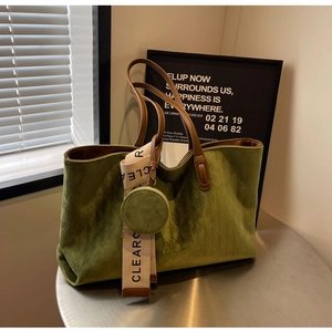Detail of green quilted tote bag with brown leather handles and wide 'CLEAR' strap