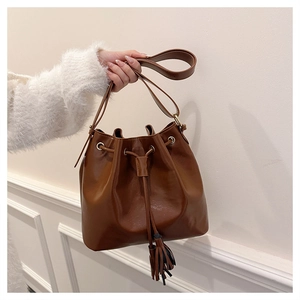 Vue détaillée d'un sac seau vintage en cuir marron avec cordon de serrage et pompon élégant
