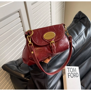 Close-up of vintage dark red leather handbag with gold metal logo and contrast stitching