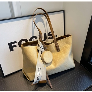 Detail of a large beige suede tote bag with diamond stitching and scarf decoration