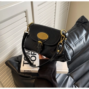 Detail of vintage black oil-wax leather bag with white contrast stitching and bronze hardware