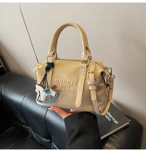 Detail of beige leather Boston bag with embossed lettering and wooden horse charm