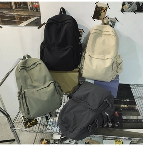 Mehrere Nylon-Rucksäcke in Schwarz, Beige, Armeegrün und Dunkelgrau auf einem Metallgestell