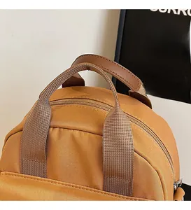 Detail of tan canvas bag with dual zippers and durable brown leather handle grip