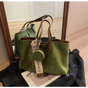 Detail of green quilted suede tote bag with leather handles and a round coin purse charm