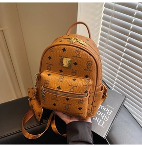Close-up of brown patterned mini backpack with golden metal logo and teddy bear charm