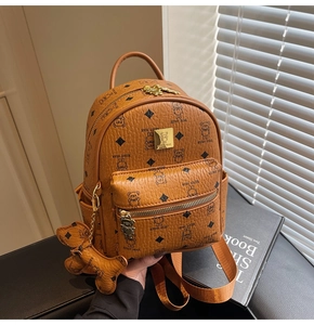 Detail of caramel mini backpack featuring bear print and golden bear metal pendant