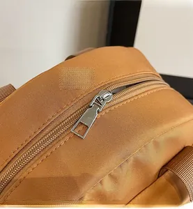 Detail shot of the smooth silver metal zipper on a durable khaki nylon crossbody bag