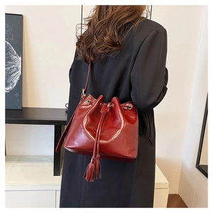 Détail du sac seau en cuir verni bordeaux avec cordons et glands décoratifs