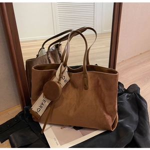 Detail of dark brown suede tote bag with a small round pouch and lettered fabric strap