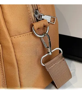 Detailed close-up of premium metal lobster clasp and thick nylon strap on caramel bag