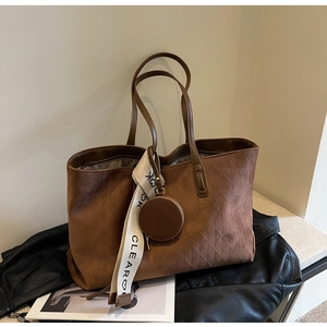 Detail of vintage brown tote bag with quilted pattern and stylish lettered woven strap