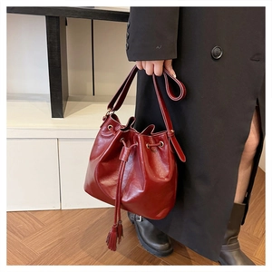 Détail du sac seau bordeaux à cordon avec des glands et des œillets métalliques dorés