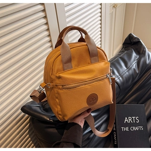Detail of yellow canvas backpack with front zip pocket and adjustable strap