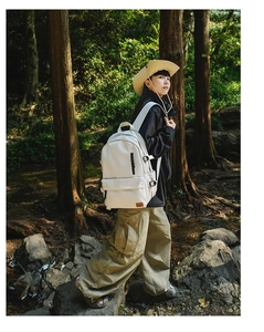 Outdoor model shot of an off-white nylon backpack with brown leather logo in a forest setting
