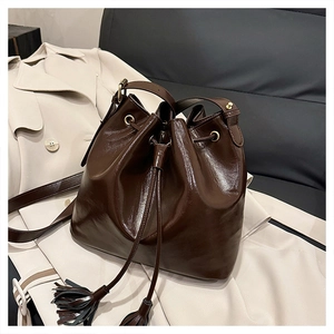 Détail du sac seau vintage marron foncé avec cordons à glands et texture en cuir poli