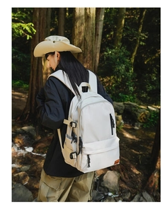 Close-up of a white waterproof nylon travel backpack with multiple pockets and side buckles